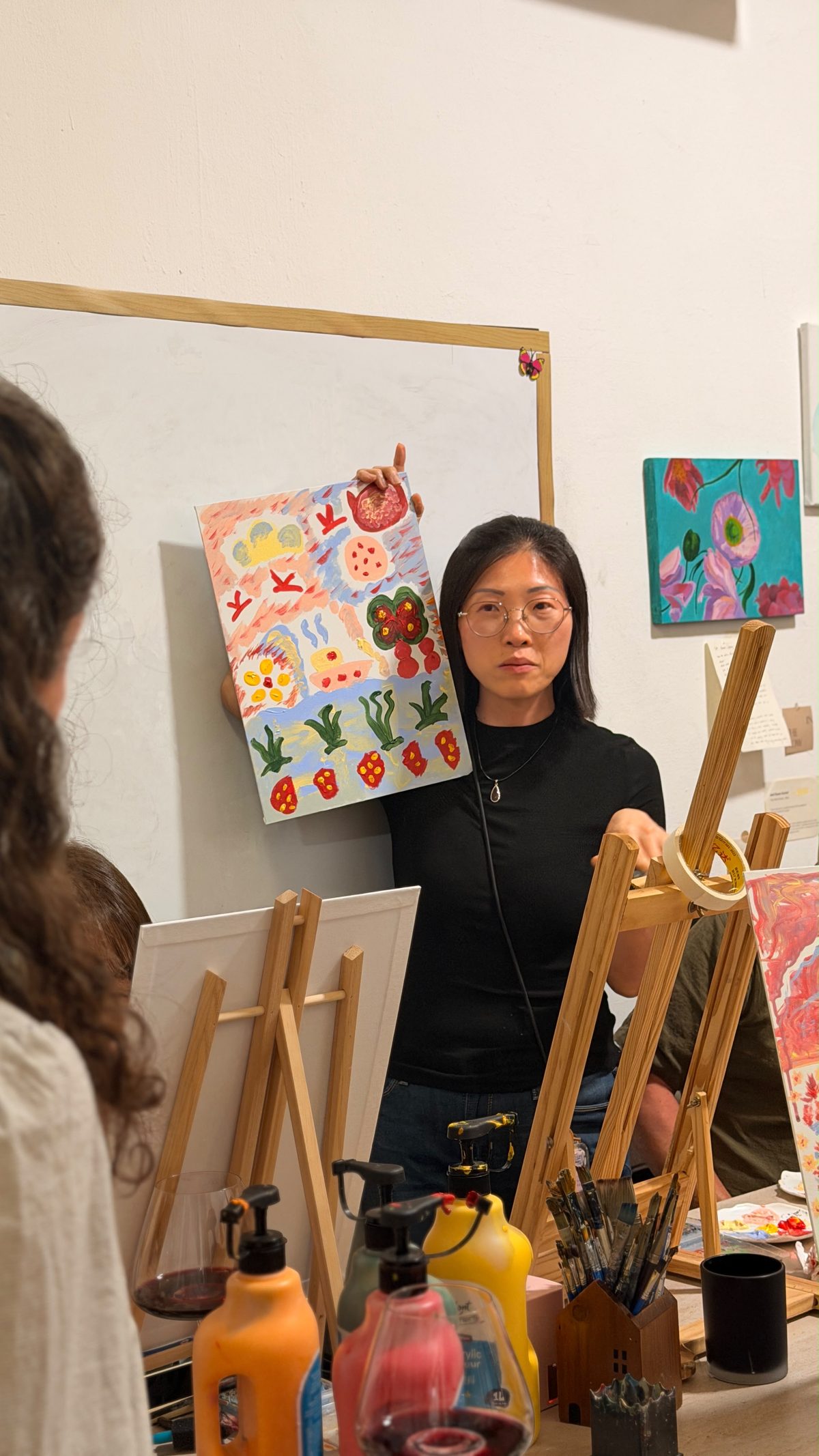 A participant showing her finished painting to the group