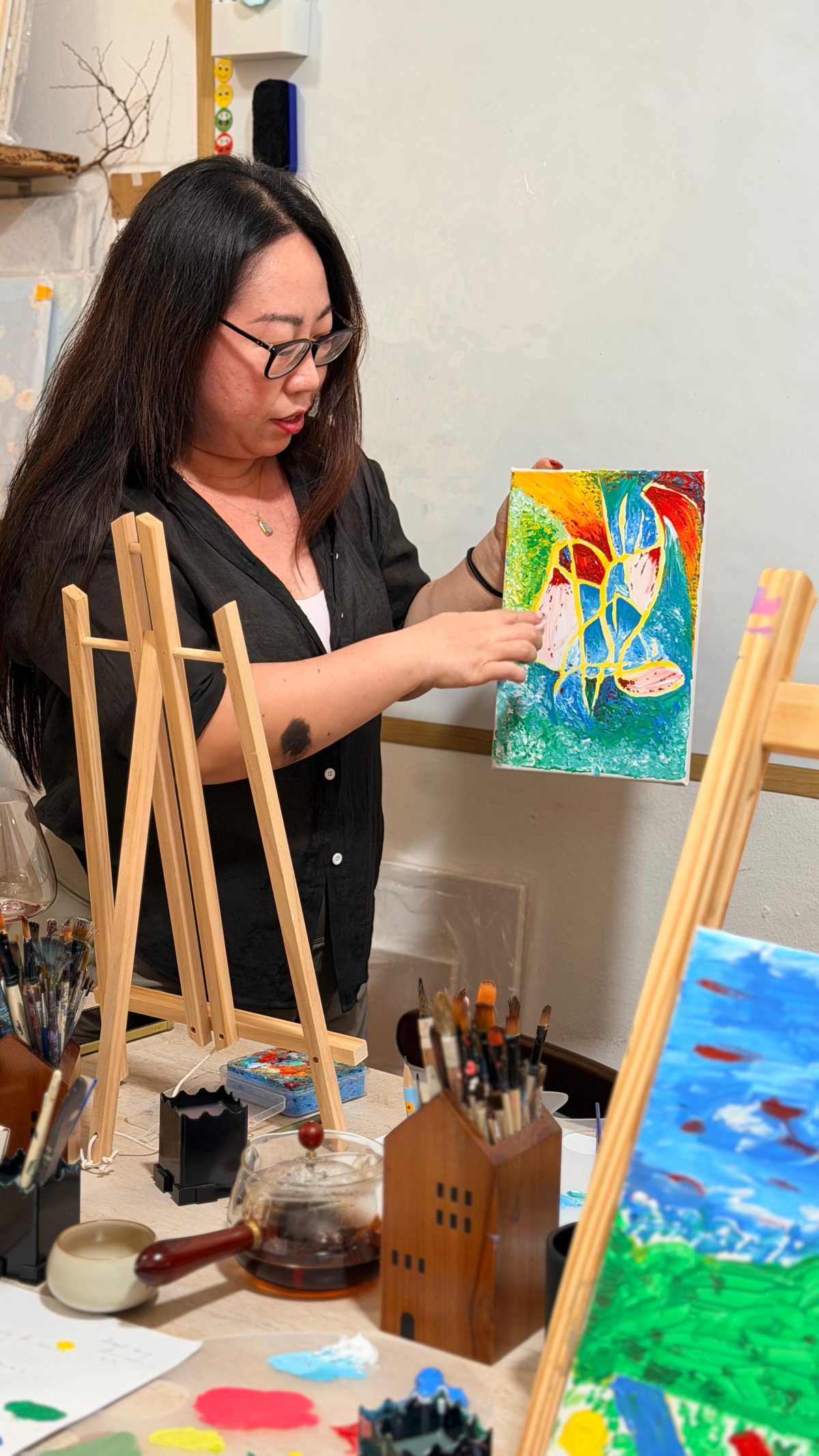 A participant holding a small, brightly coloured painting