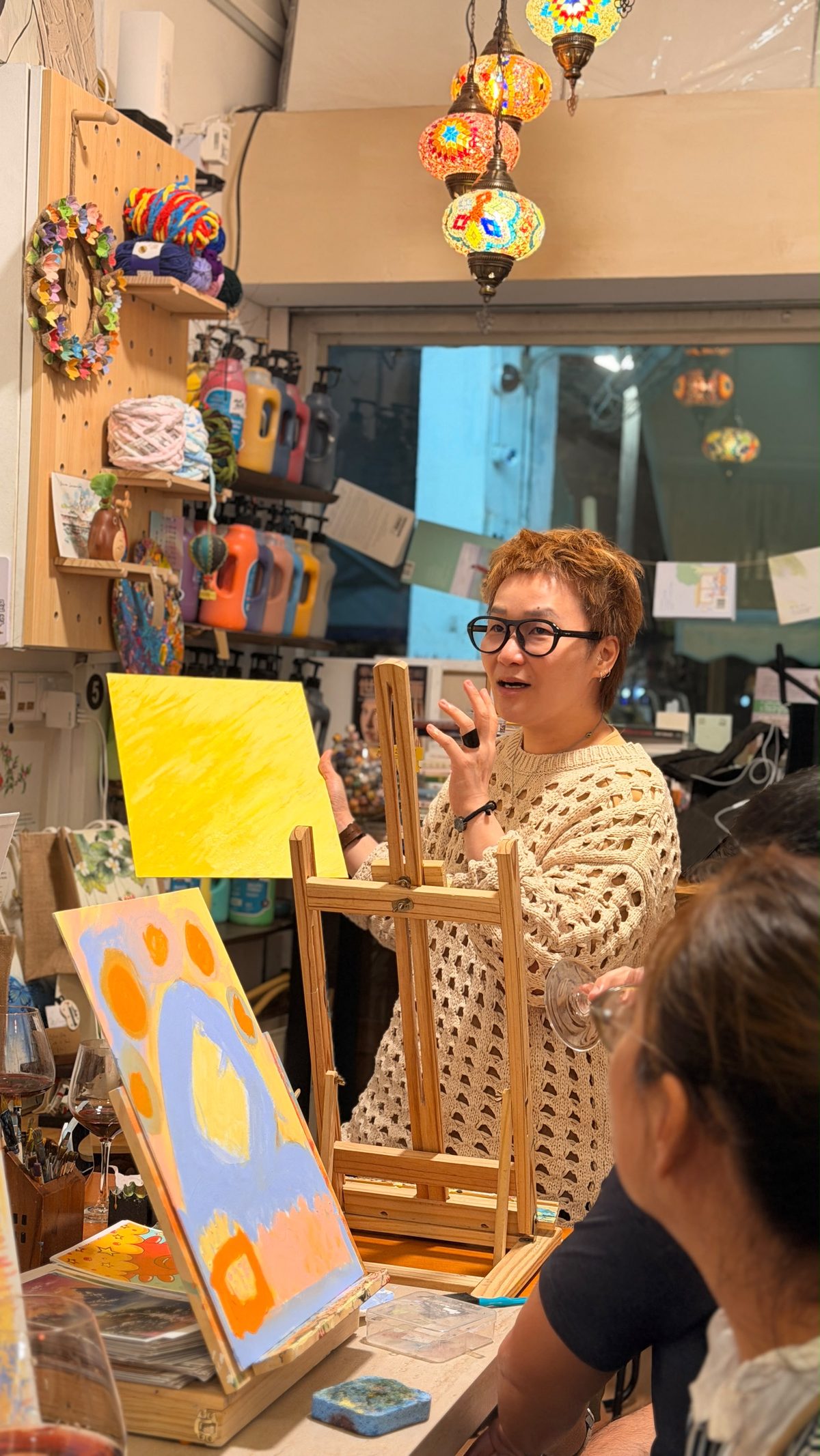A participant holding up a yellow painting and talking about it