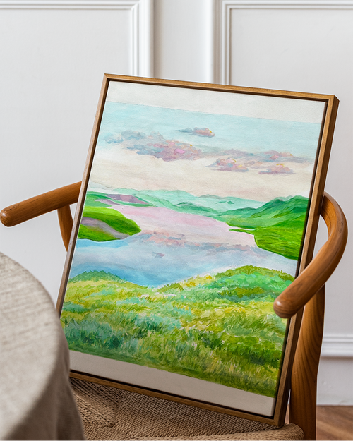 Framed landscape painting on a wooden chair against a white wall