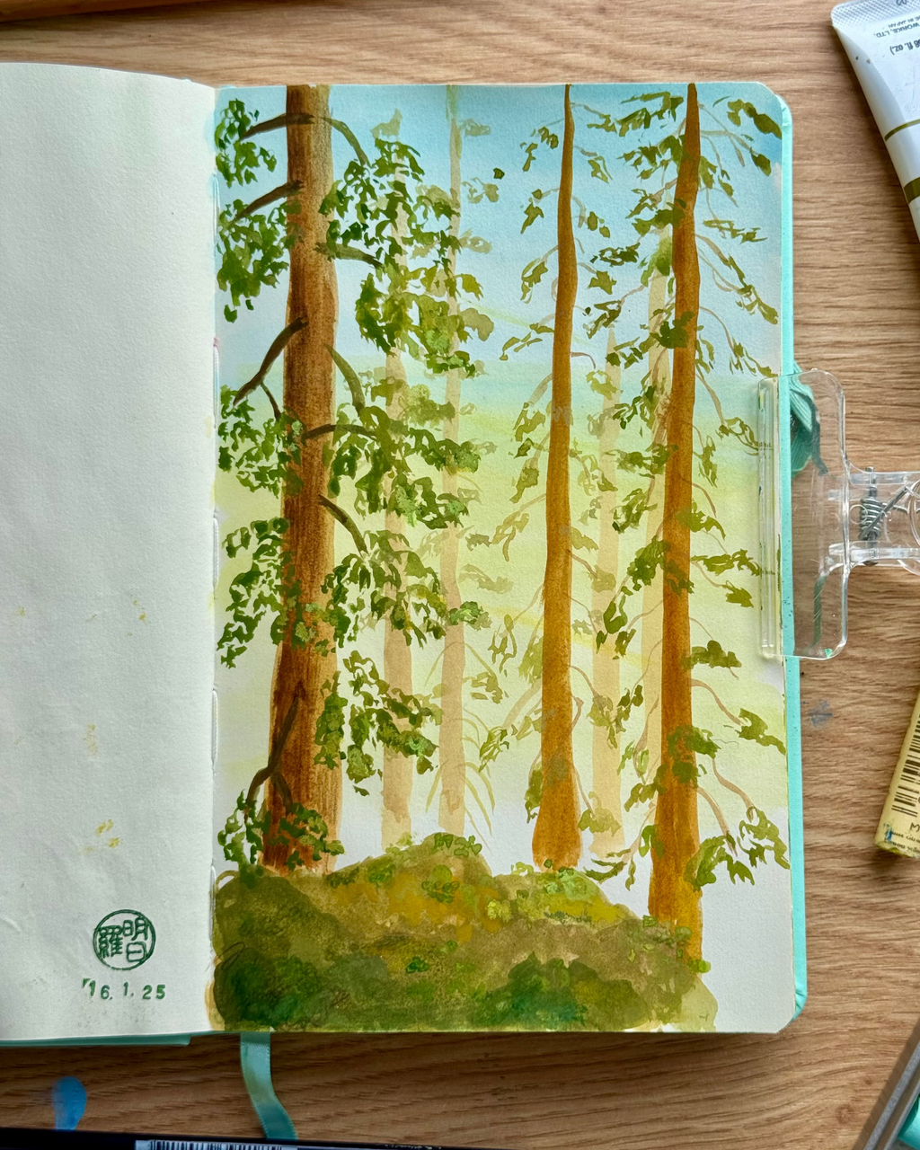Notebook with a forest illustration on the cover, placed on a wooden surface.